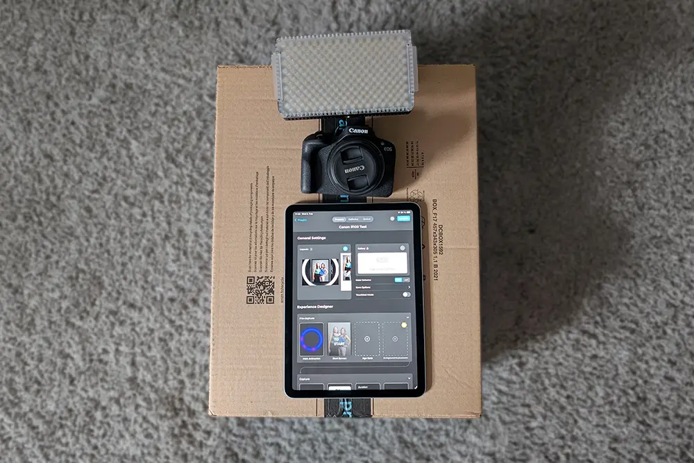 iPad, camera and light on top of the original cardboard box. iPad, camera, and light on cardboard box